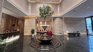 Eine moderne Lobby mit einem zentralen Wasserspiel, einer Sitzecke und einer Rezeption.