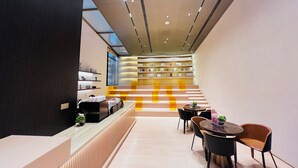 Eine moderne Hotelhalle mit Empfangsschalter, Sitzgelegenheiten und einer Treppe zum zweiten Stock.