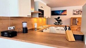 Eine moderne Küche mit Holzarbeitsplatten, weißen Schränken, einem eingebauten Herd und einer Bar mit Hockern.