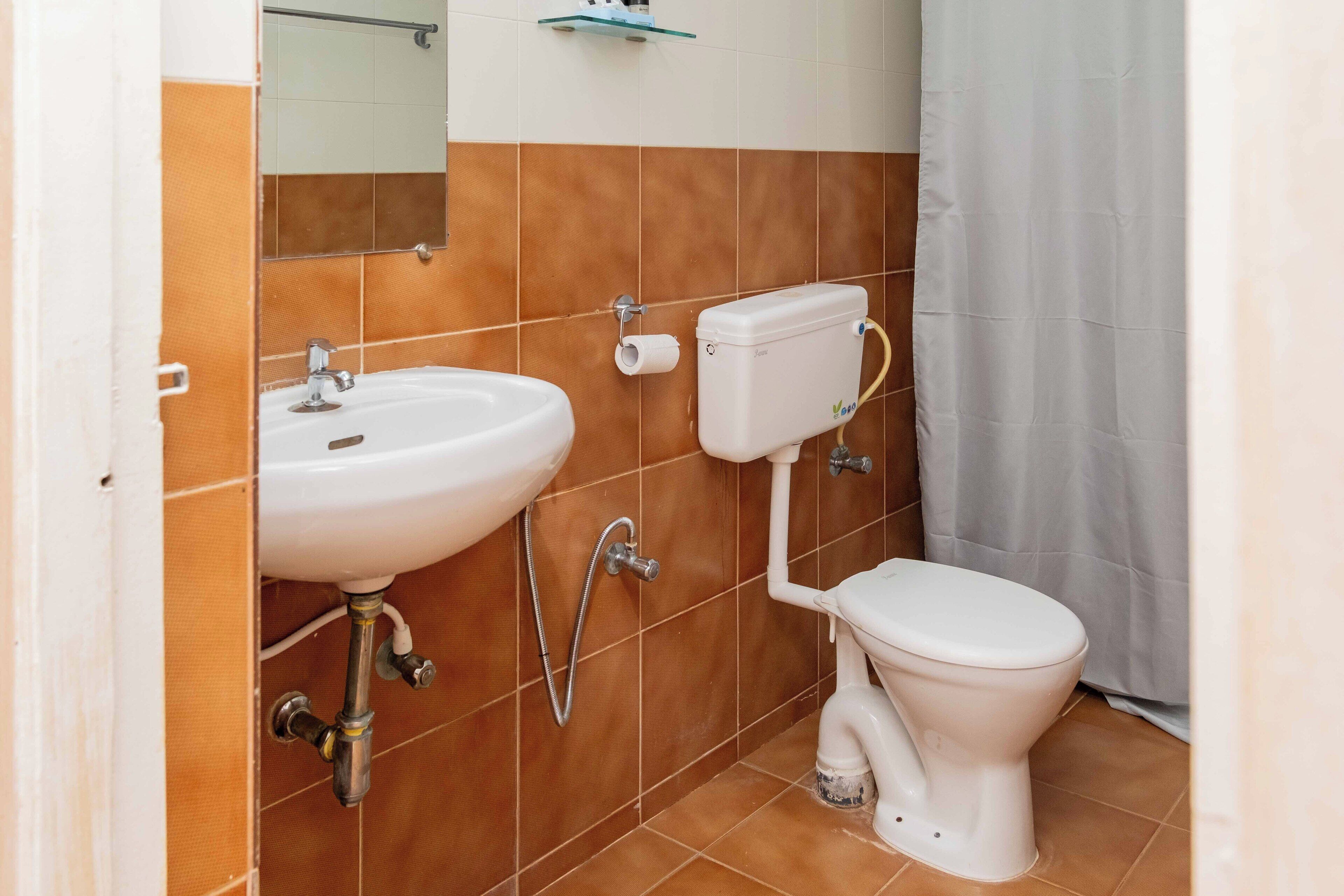 Une salle de bain avec un lavabo blanc, des toilettes et une pomme de douche.