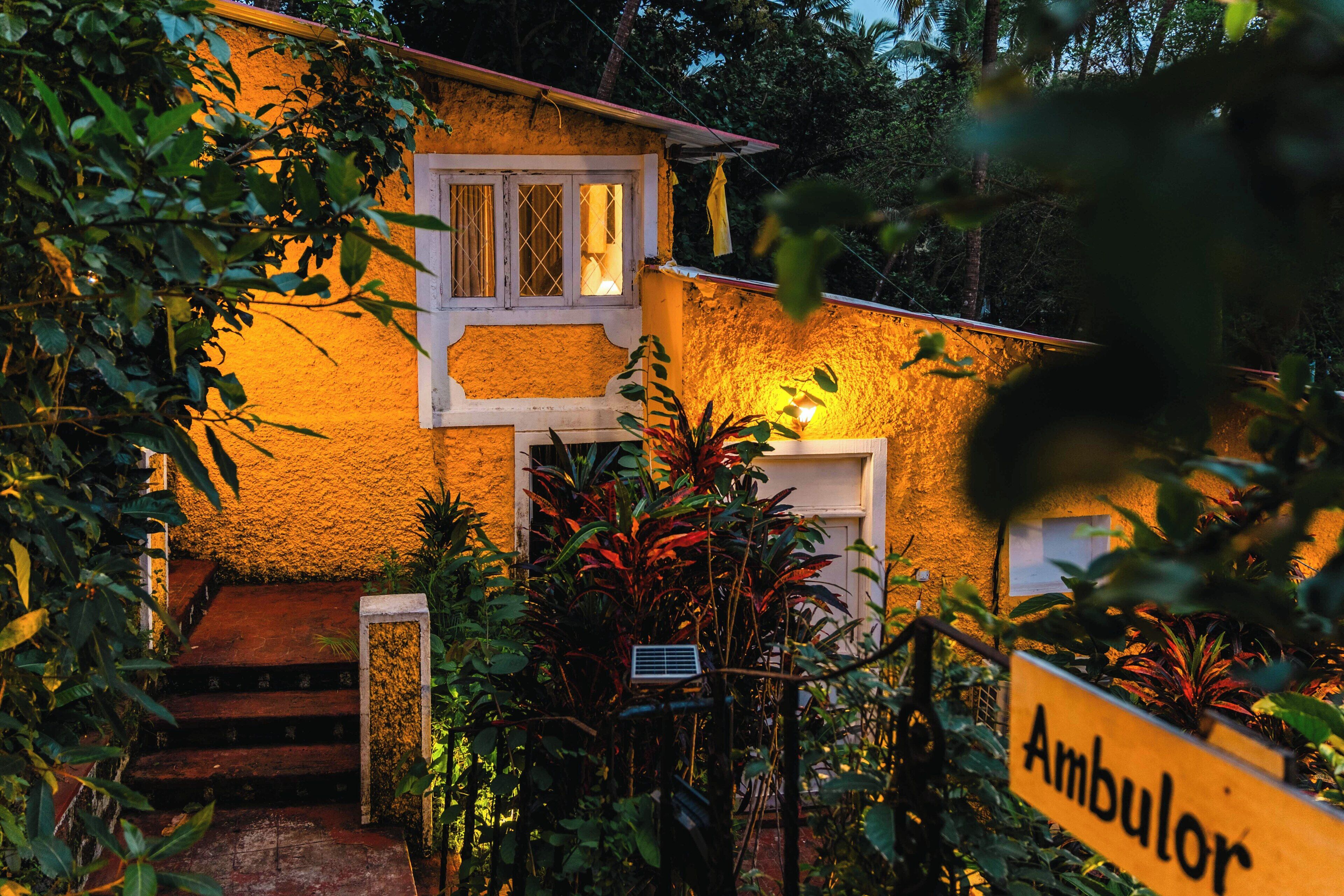 A rustic house with a sign reading "Ambulor" and a staircase leading to the entrance.