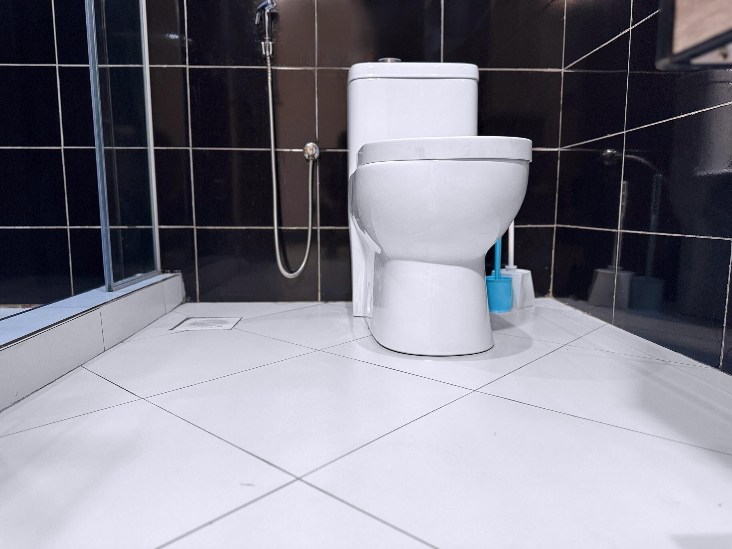 Une salle de bain moderne équipée de toilettes, d’une douche et d’une porte en verre.
