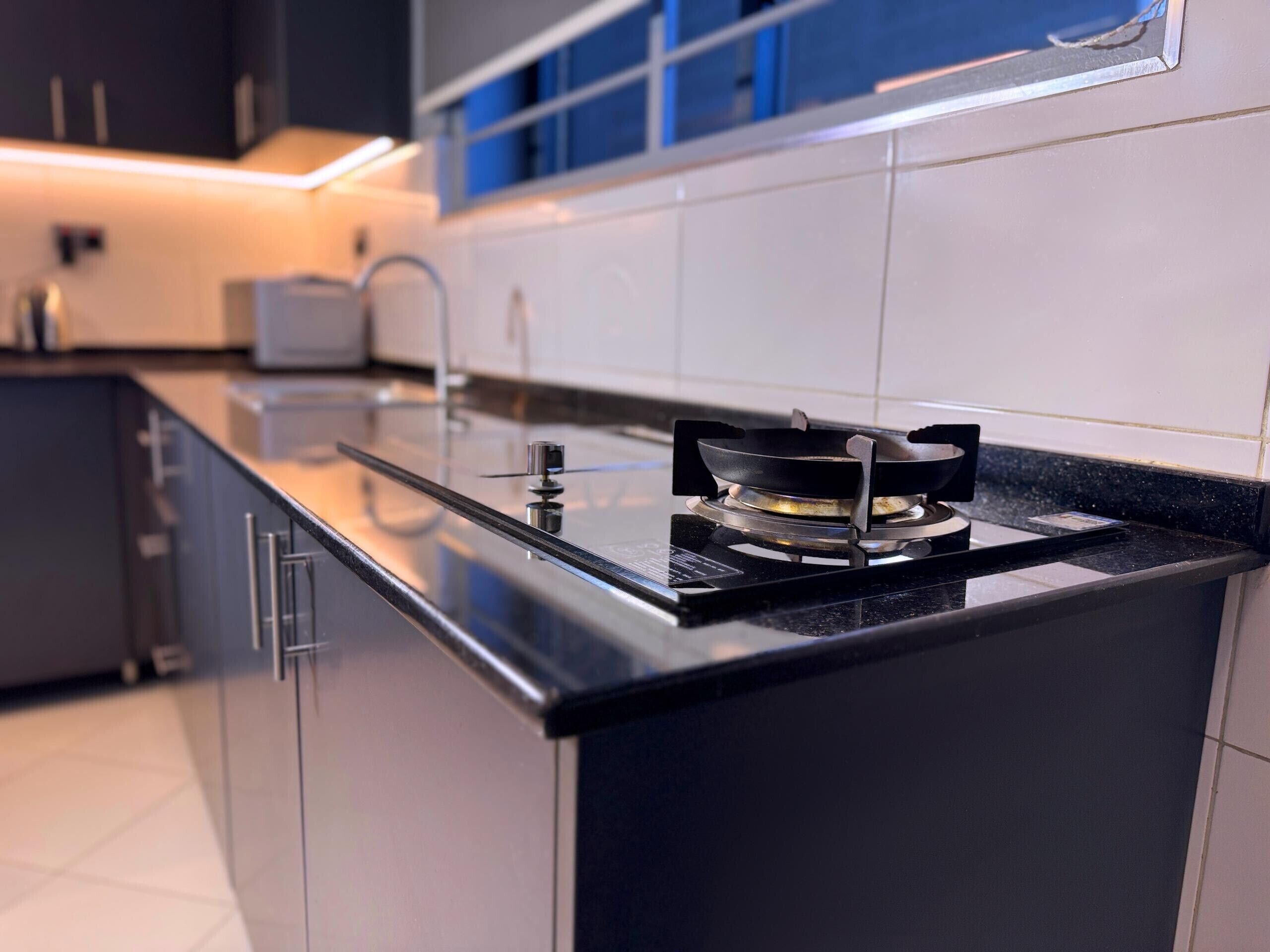 A modern kitchen with a gas stove, black countertops, and white cabinets.