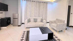 A modern living room with a sofa, a coffee table, and a TV. - RD Homes Bunga (Kampala)
