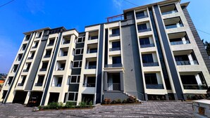 A multi-story residential building with a central staircase, balconies, and a paved entrance area. - RD Homes Bunga (Kampala)