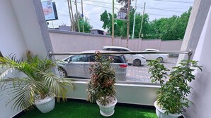A balcony with artificial green turf, potted plants, and a view of parked cars and buildings. - RD Homes Bunga (Kampala)