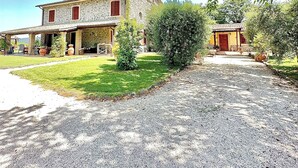 A two-story stone house with a gravel driveway and a well-maintained lawn. - Villa of Silence-Peace and Wellness in the Vineyards of Orvieto (Umbria)