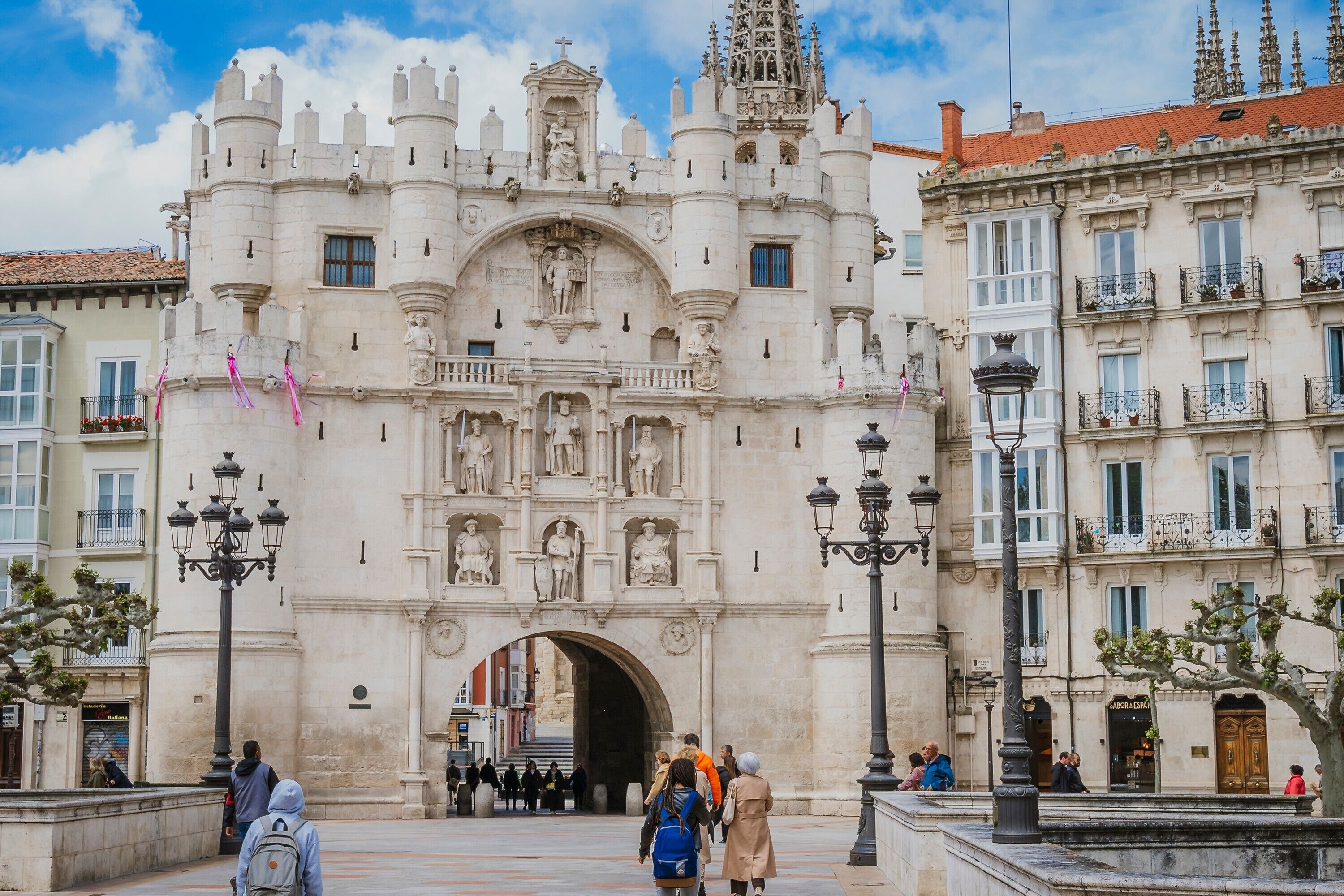 A historic building with a large archway, ornate statues, and a clock.