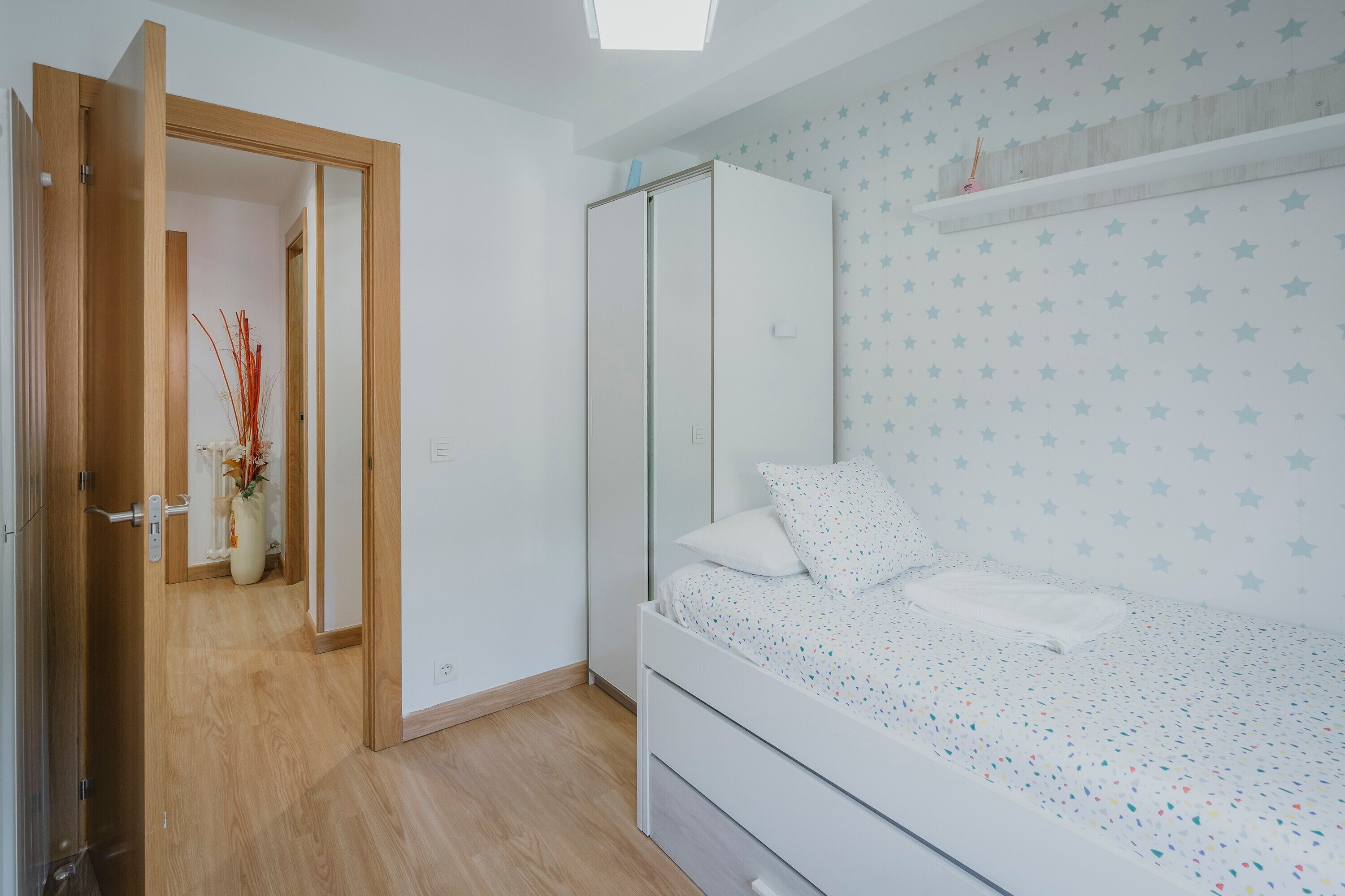 Ein Schlafzimmer mit Bett, Kleiderschrank und einer Tür zu einem anderen Raum.