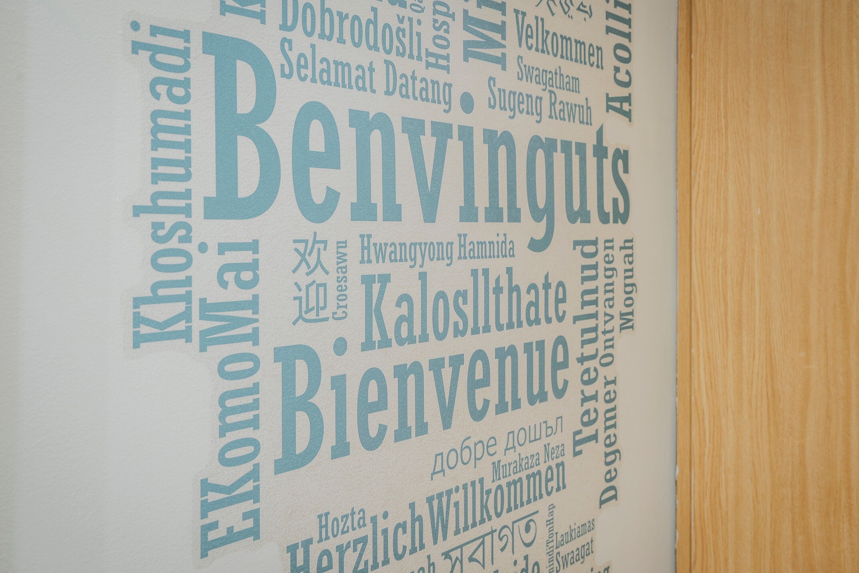 A wall with various words in different languages, likely indicating multilingual signage or a welcome message.