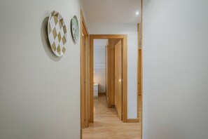 Un pasillo con puertas de madera, una pared de color claro y un objeto blanco pequeño en el suelo.