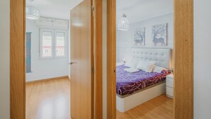 Een slaapkamer met een bed, nachtkastje, een kroonluchter en kunst aan de muur.