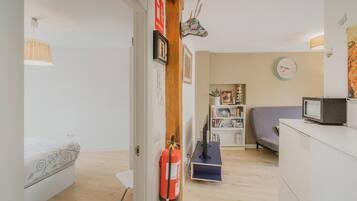 Una habitación con cama, escritorio, estantería, televisor y extintor.