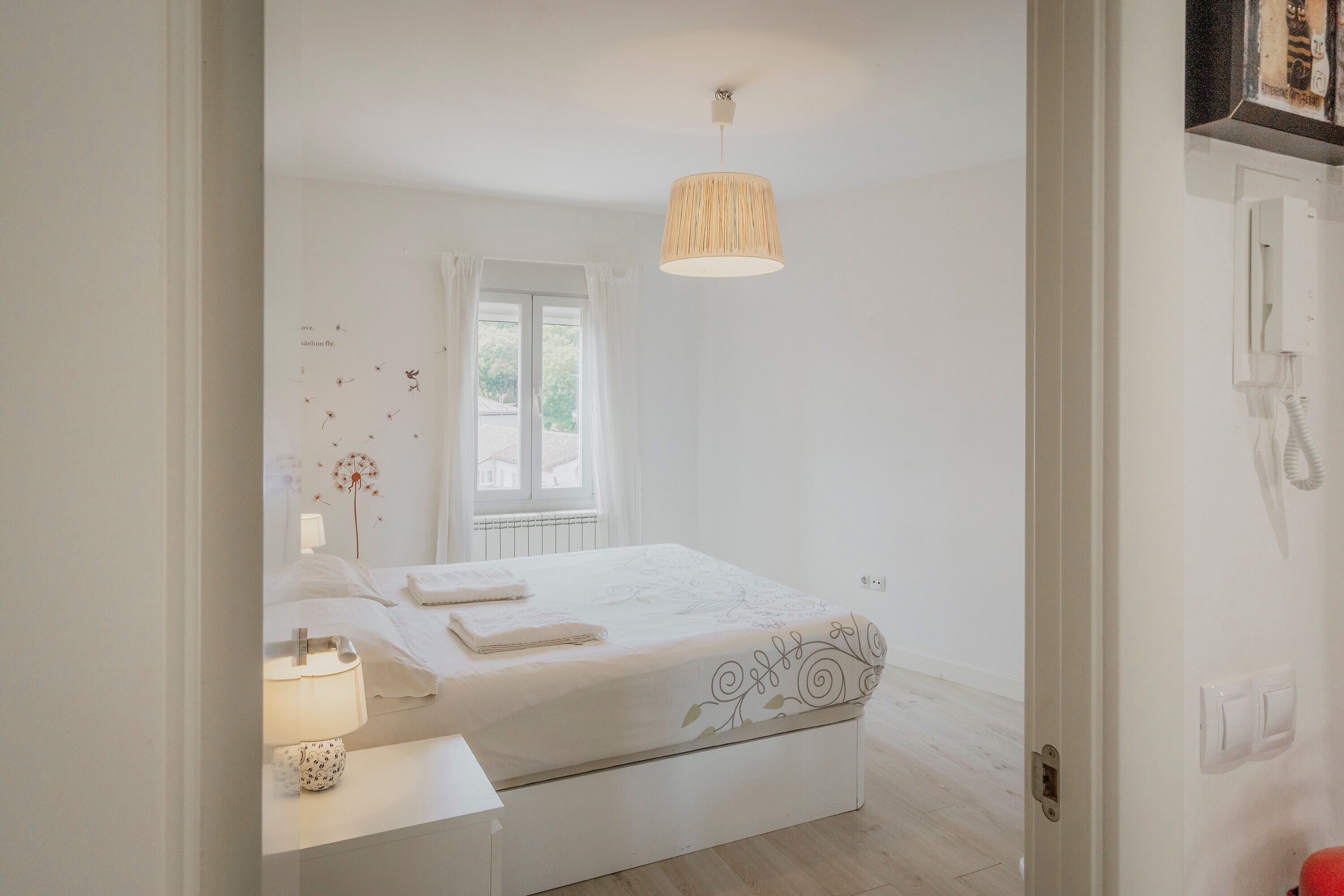 Une chambre à coucher avec un lit, une table de chevet, une lampe et un luminaire suspendu.