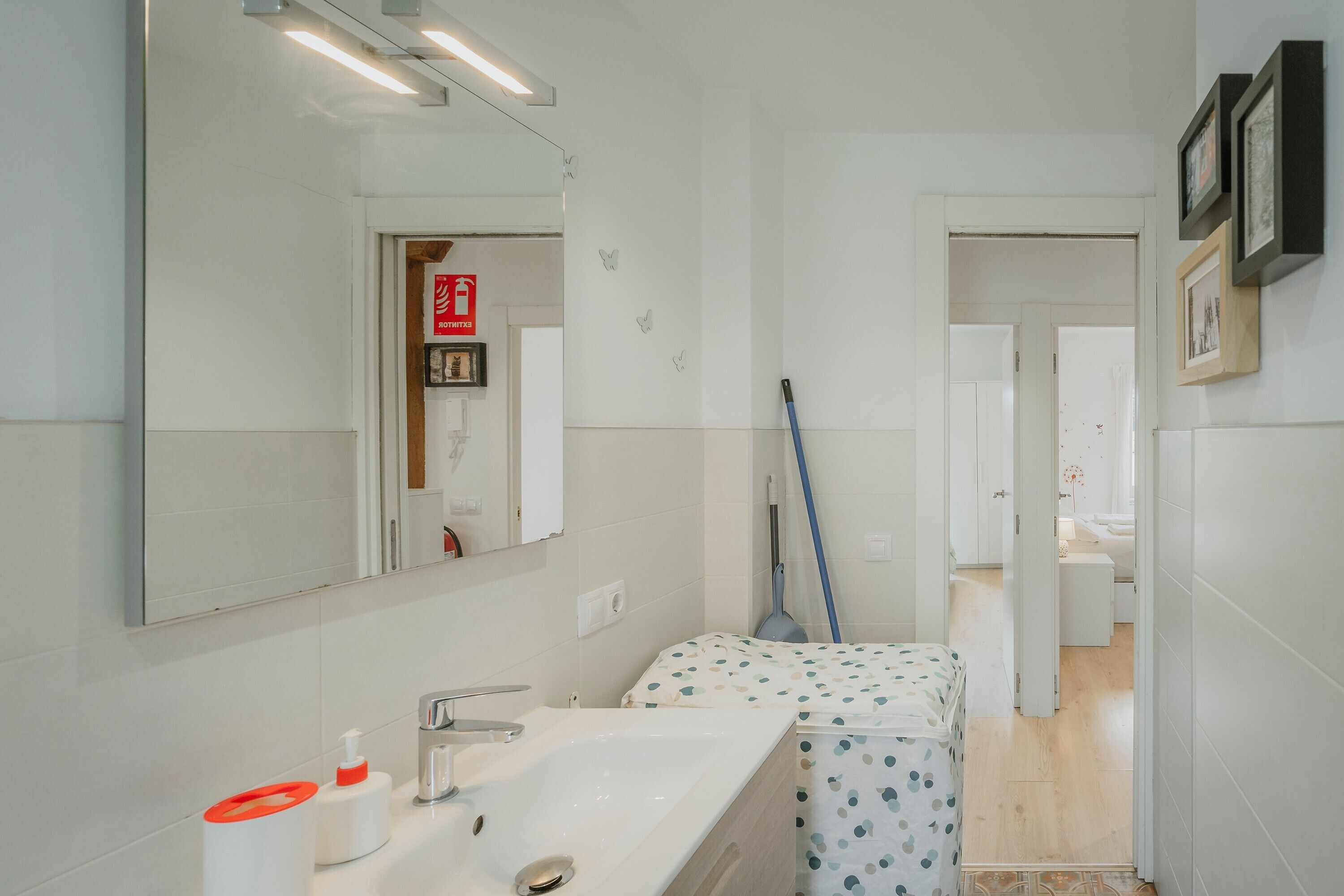 Un baño moderno con un espejo grande, un lavamanos, un inodoro y una zona de ducha.