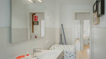 Un baño moderno con un espejo grande, un lavamanos, un inodoro y una zona de ducha.