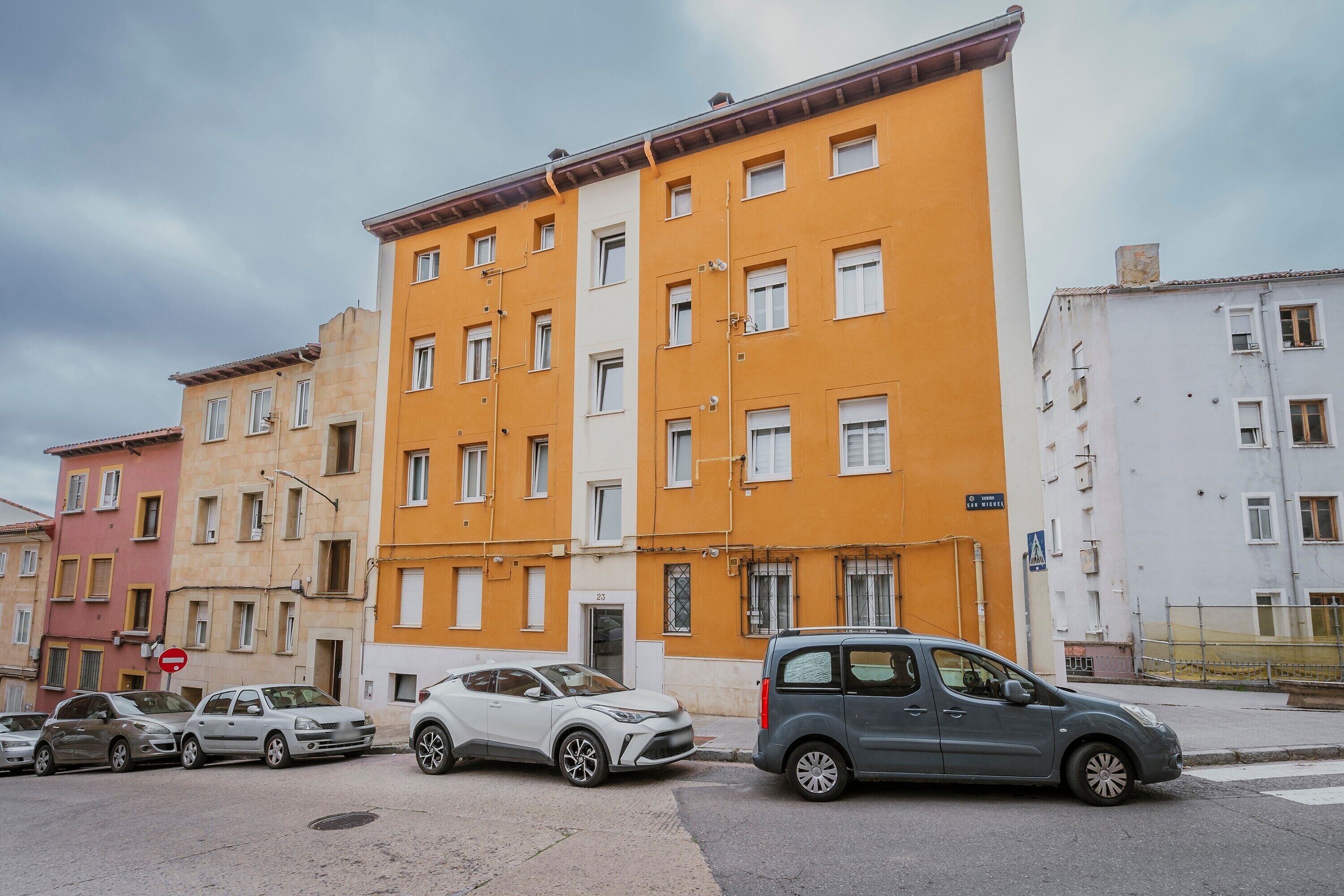 A multi-story building with a row of parked cars in front.