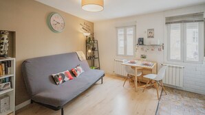 A cozy living room with a sofa, a dining table with chairs, a bookshelf, and a wall clock. - Apartment 'Loló Vut' with Wi-Fi (Burgos)