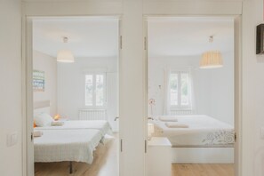 Une chambre avec deux lits, un radiateur, une fenêtre et une lampe suspendue.