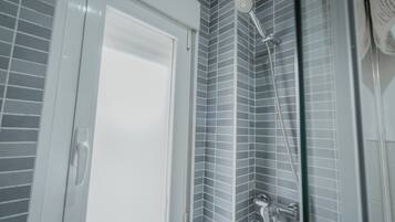 Une salle de bain avec une douche, des murs carrelés et une porte blanche.