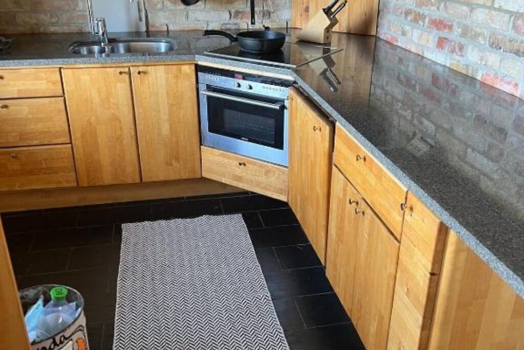 A kitchen with wooden cabinets, a built-in oven, a sink, and a granite countertop.