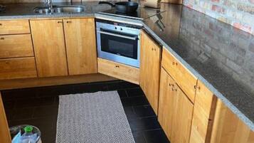 A kitchen with wooden cabinets, a built-in oven, a sink, and a granite countertop.