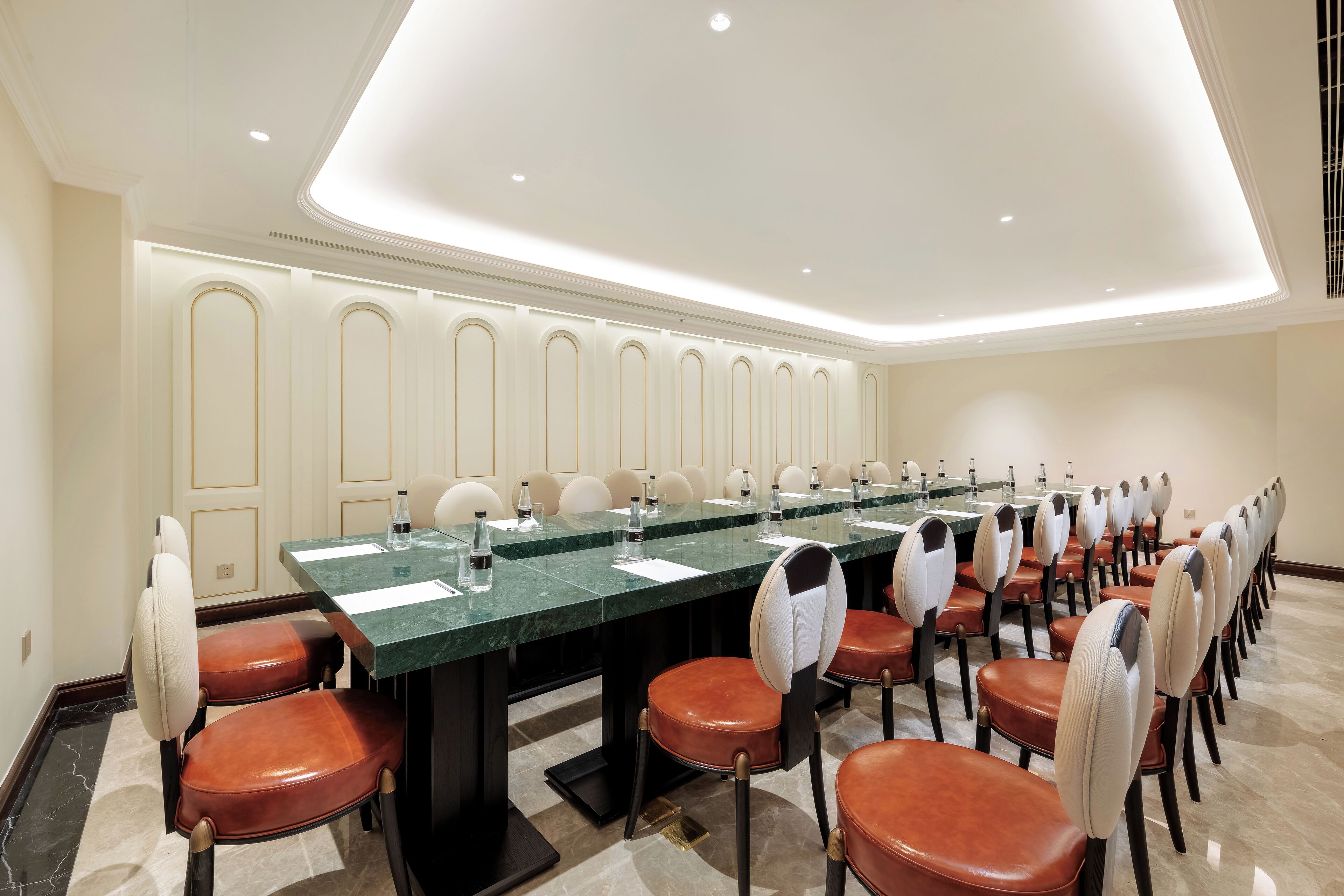 A conference room with a long table, multiple chairs, and a modern ceiling design.