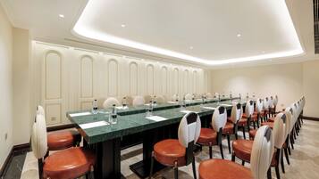 A conference room with a long table, multiple chairs, and a modern ceiling design.