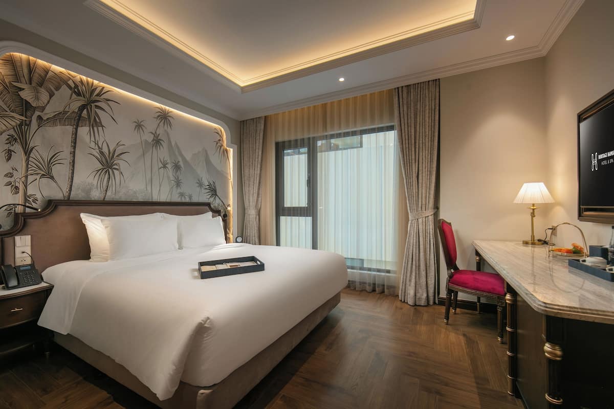 Een hotelkamer met een groot bed, een bureau met stoel, een telefoon en een televisie.
