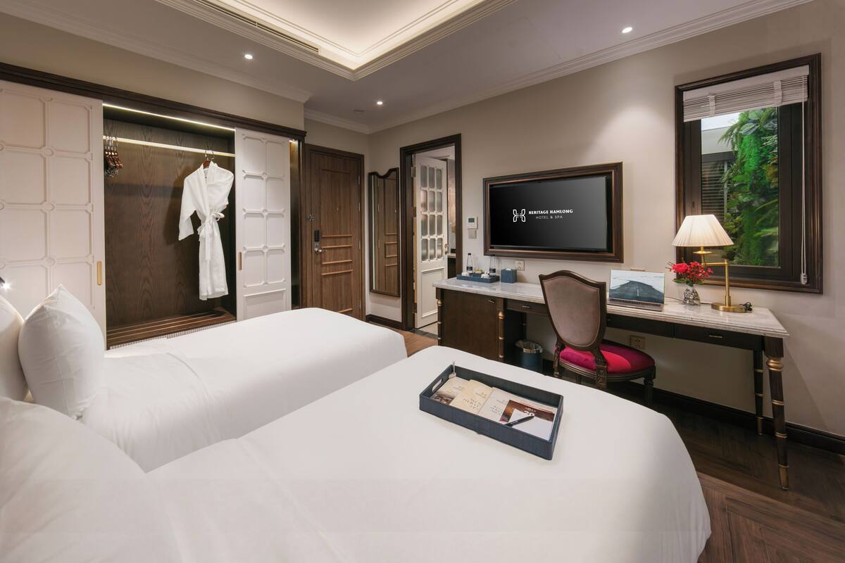 Een hotelkamer met twee bedden, een bureau, een televisie en een raam met uitzicht.