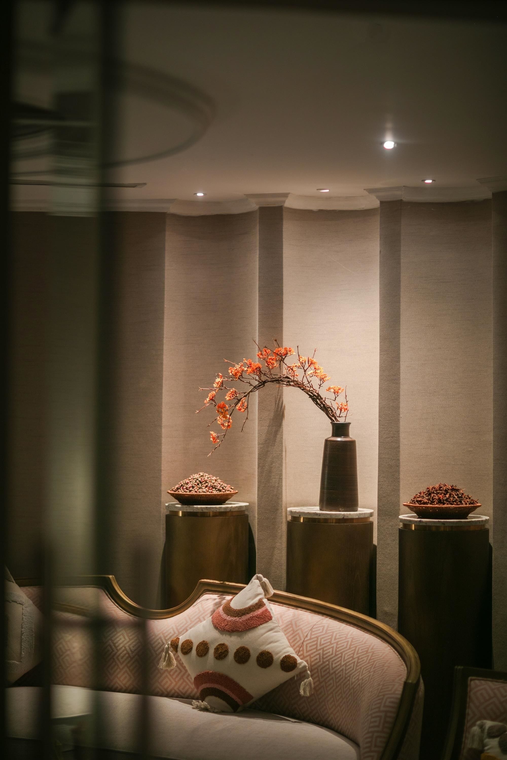 A modern hotel room with a bed, a vase with flowers, and two side tables.