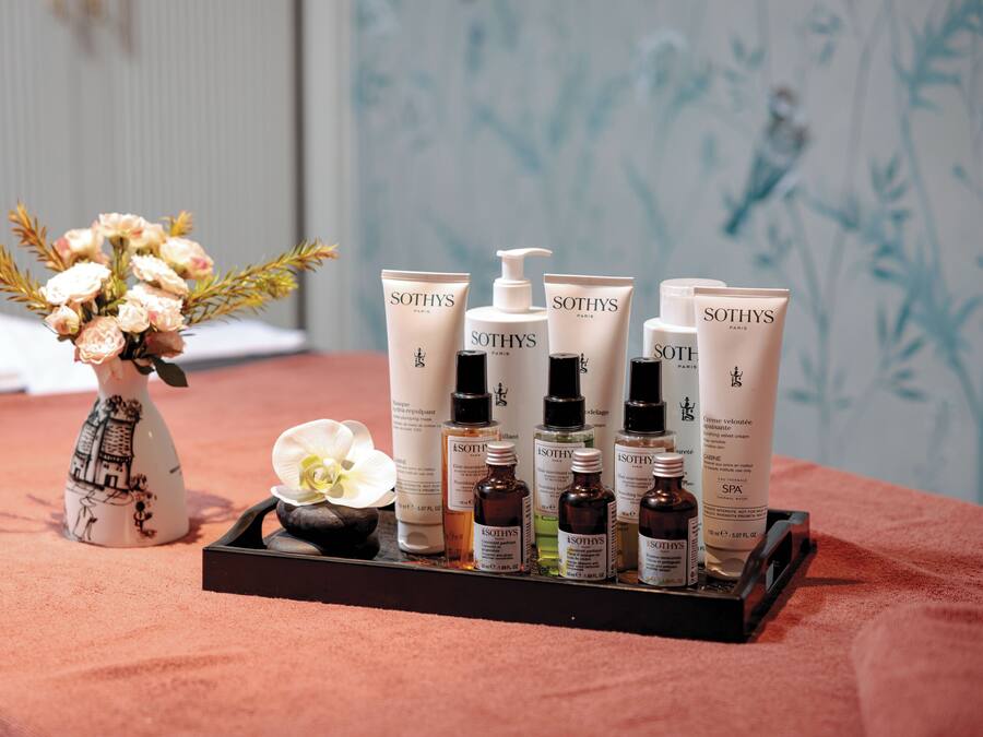 A tray with various Sothys Paris skincare products and a vase with flowers on a textured surface.