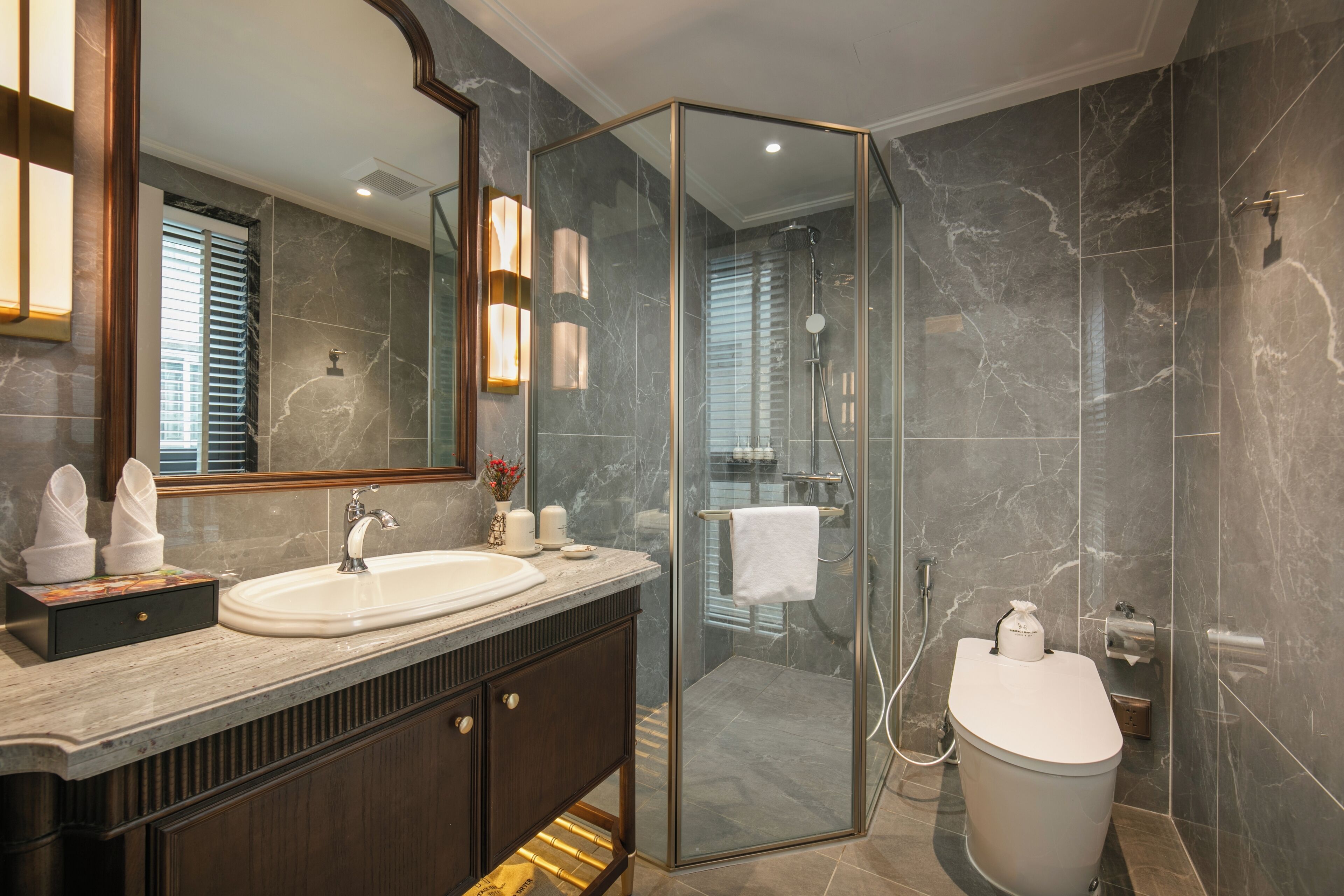 Un baño moderno con ducha envuelta en vidrio, un espejo grande y encimera de mármol.