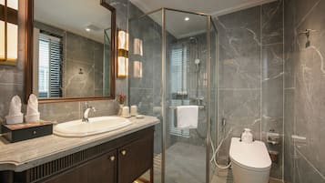 Un baño moderno con ducha envuelta en vidrio, un espejo grande y encimera de mármol.