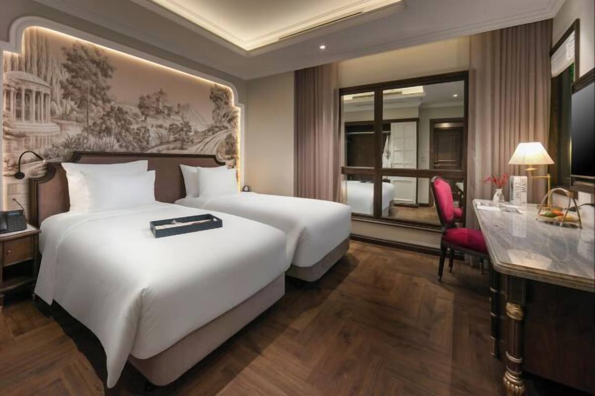 Een hotelkamer met twee bedden, een bureau, een stoel en een groot raam.