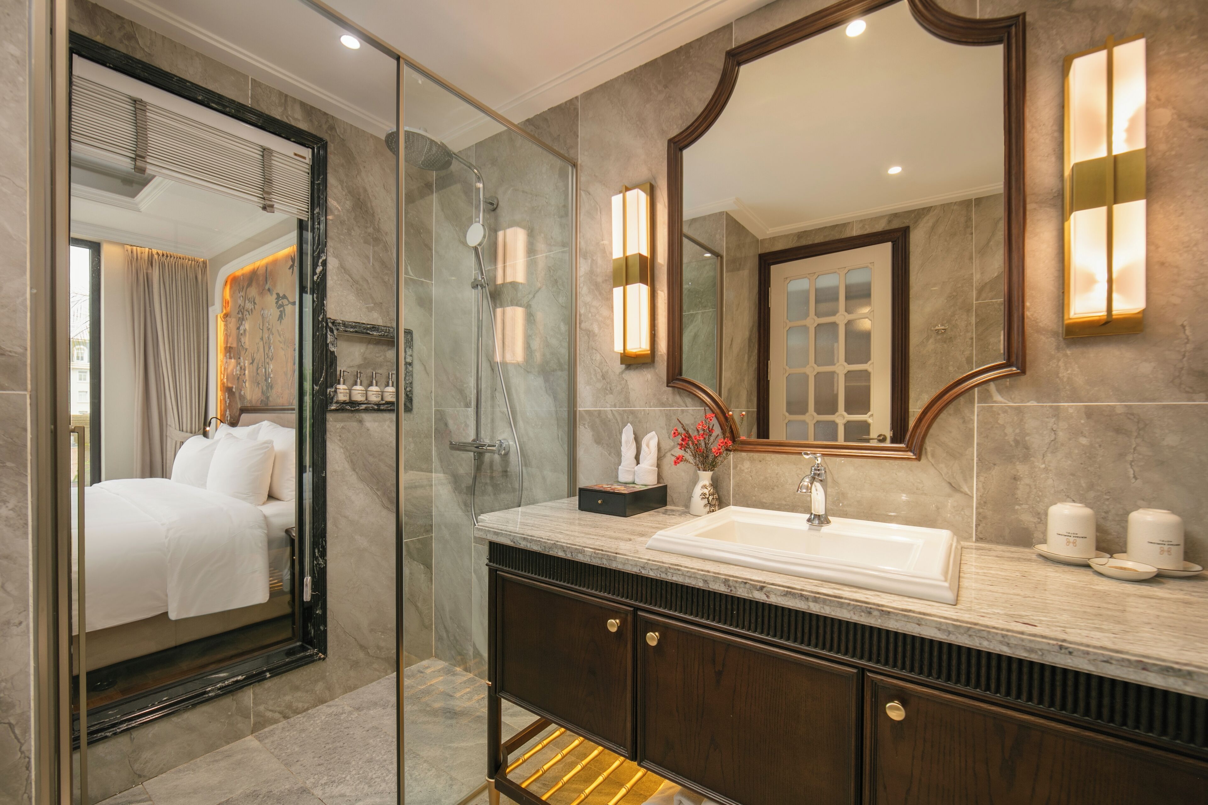 A modern bathroom with a glass-enclosed shower, a large mirror, and a marble countertop.