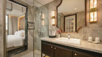 A modern bathroom with a glass-enclosed shower, a large mirror, and a marble countertop.