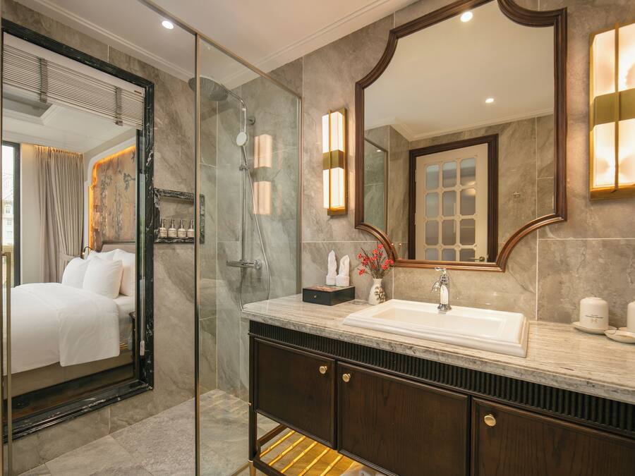 A modern bathroom with a glass-enclosed shower, a large mirror, and a marble countertop.