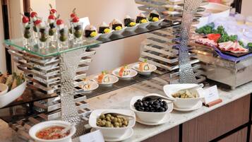 A buffet with various food items including sushi, olives, and a salad.