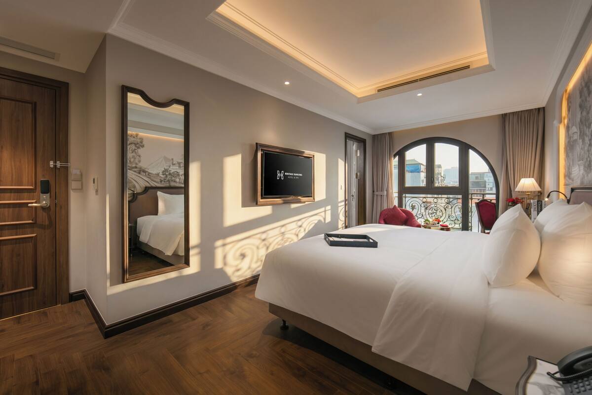 Een hotelkamer met een groot bed, een flatscreen-tv, een balkon met uitzicht en een houten deur.