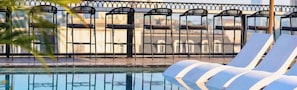 Zona junto a la piscina con sillas de descanso y una valla de metal.