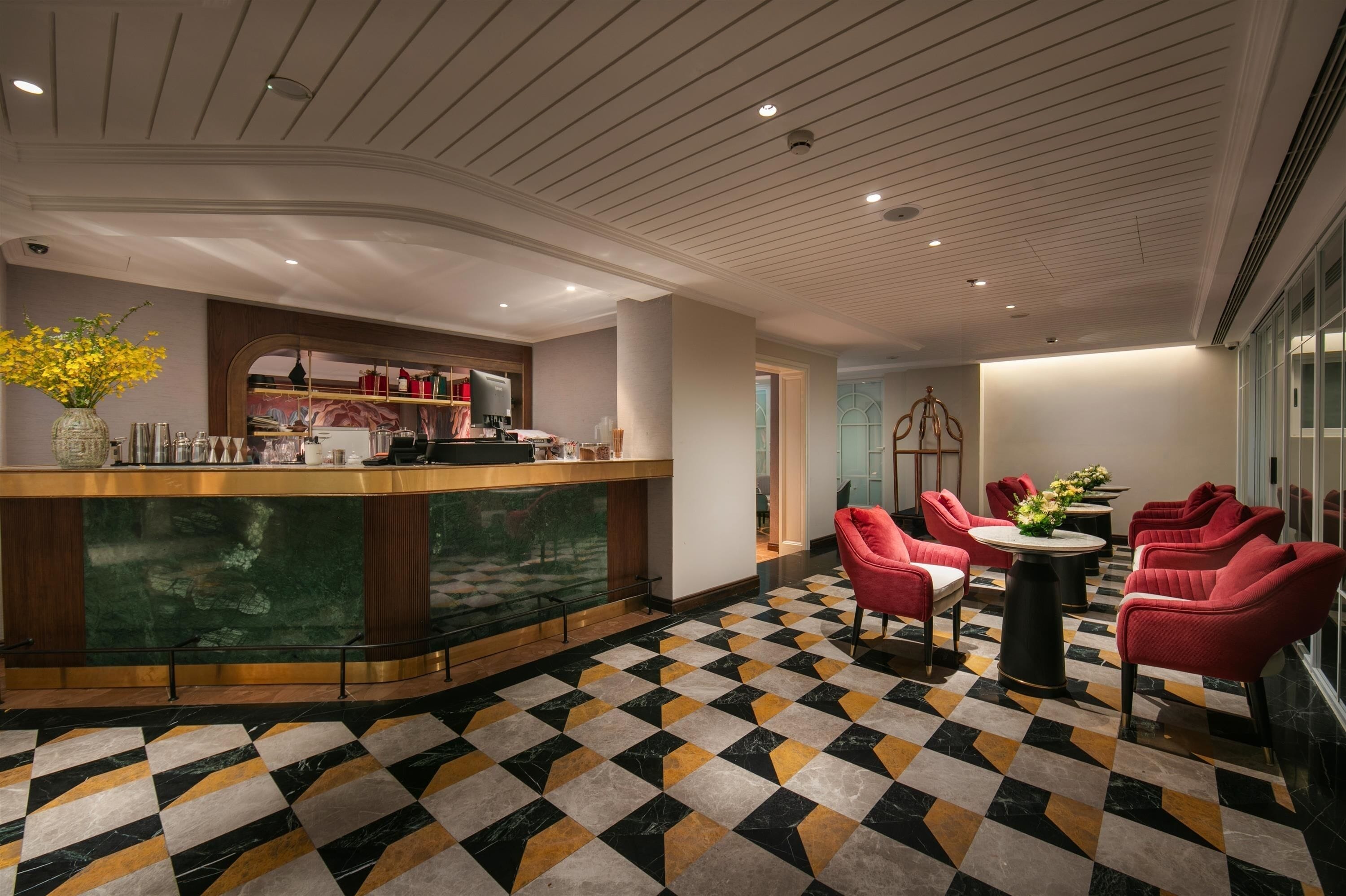 A lobby with a check-in counter, seating area, and a patterned floor.