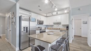 A modern kitchen with stainless steel appliances, white cabinetry, and a central island with bar stools. - Gulf Views and Tons of Amenities, 2BR 2BA at the Laketown Wharf! (Panama City Beach)