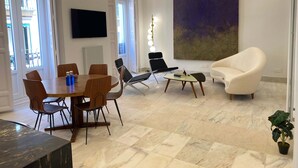 Una sala moderna con comedor, un cuadro abstracto grande y una planta en maceta.