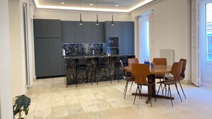 Una cocina moderna con gabinetes oscuros, encimera de mármol e iluminación colgante.