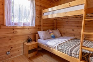 A wooden cabin room with bunk beds, a small bedside table, and a window with lace curtains. - Holiday Homes, Summer Pool, Whirlpool, Sauna (Mielno)