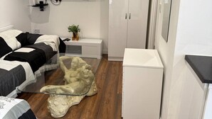 A bedroom with a bed, a TV, a wardrobe, and a decorative sculpture on a glass table. - Nice 1-bedroom apartment in Milton Keynes (Milton Keynes)