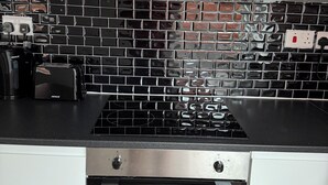 A kitchen with a black tiled backsplash, stainless steel appliances, and white cabinetry. - Nice 1-bedroom apartment in Milton Keynes (Milton Keynes)