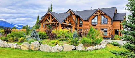 A log cabin with a stone foundation and a well-maintained garden.