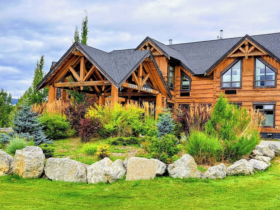 A log cabin with a stone foundation and a well-maintained garden.